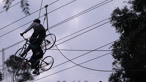 A cyclist passes beneath a network of power lines in an urban setting.