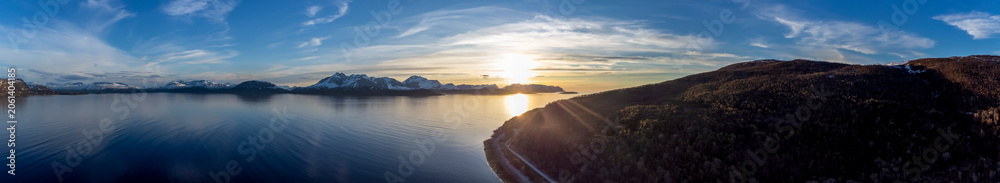 Fototapeta premium Panoramic drone shot overlooking the midnightsun on Fjord ( Reisafjorden ) and mountain Trolldalstinden in Storeng Kvaenangen, Troms, Norway