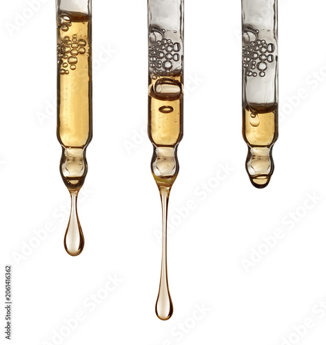 Glass pipettes with drops of cosmetic serum and air bubbles