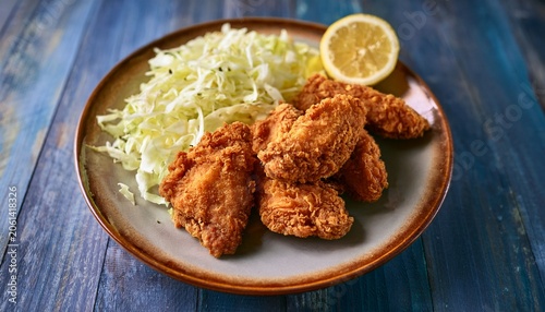 deliciously golden and crispy fried chicken pieces beautifully presented on a rustic plate alongside fresh shredded cabbage and a zesty lemon wedge ready to be enjoyed as a flavorful meal