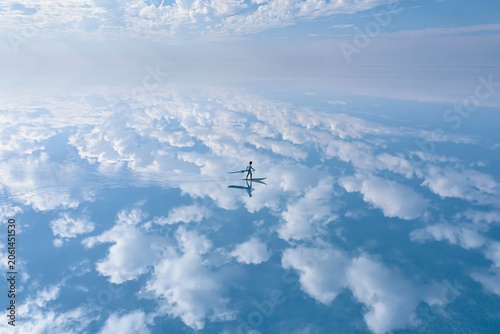 Healing scenery, breathtakingly beautiful. Vast blue sky with white clouds, boundless mirror-like water surface with a surfer