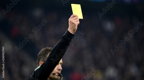 Soccer Referee Holding Up Yellow Card in Crowded Stadium