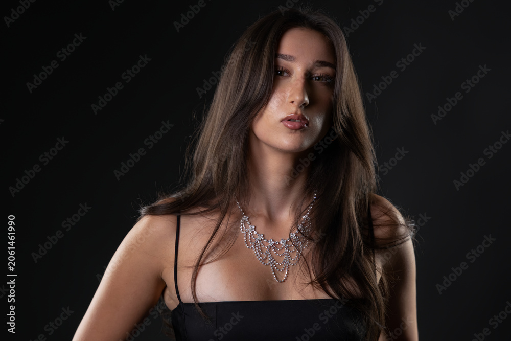 Fototapeta premium Female model wearing a beautiful sparkling diamond necklace and black dress in studio