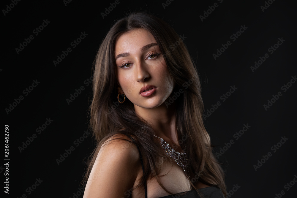 Naklejka premium Young woman posing for a fashion and beauty portrait against a dark background