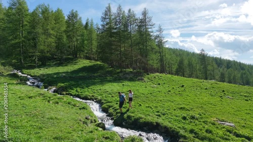 Couple crossing a mountain stream immersed in a lush green landscape