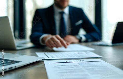HR manager meeting with a candidate while reviewing resumes, paperwork, and employment documents for a finance vacancy or business role. 