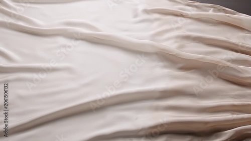 Close up of flowing white silk fabric with soft folds and gentle shadows on a neutral background