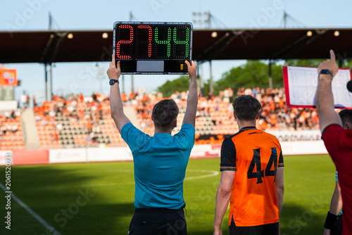 Assistant referee displaying substitution board during a soccer match with stadium crowd in the background