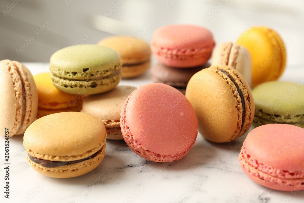 Fototapeta premium Different tasty macarons on white marble table indoors, closeup