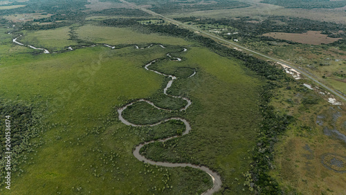 Foto Aerial view of meandering river winding through vast green plains with highway n