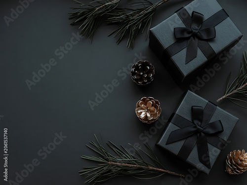 Two black gift boxes with ribbons and pine branches on dark background for christmas or holiday decoration ideas