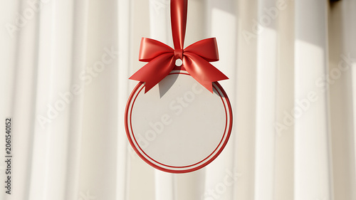 A red ribbon tied around a circular ornament hanging from a white curtain with natural light shining through the folds