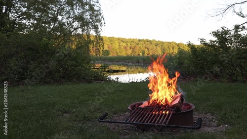 Campfire at sunset before a calm wetland at a scenic campsite
