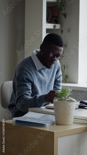 Dolly away shot of young adult African American male developer working on computer near Caucasian colleague in office. Clip ideal for corporate wellness and software development marketing