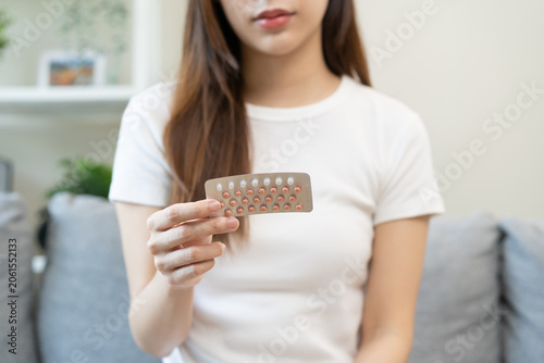 Contraception and pregnancy, menstruation concept, birth control pills asian young woman hand holding hormonal oral contraceptive medicine, take pharmaceutical to prevention, safe virus sex disease.