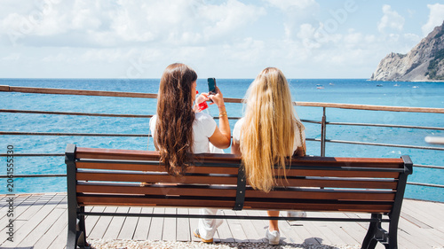 Tableau sur toile Deux jeunes femmes assises sur un banc regardant la mer méditerranée
