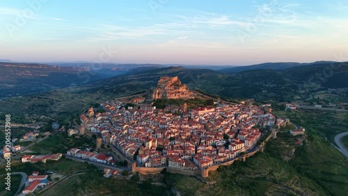 Aerial view of Morella, medieval walled town with complete perimeter walls and hilltop castle at sunrise, Els Ports valley landscape, Castellon, Valencian Community, Spain