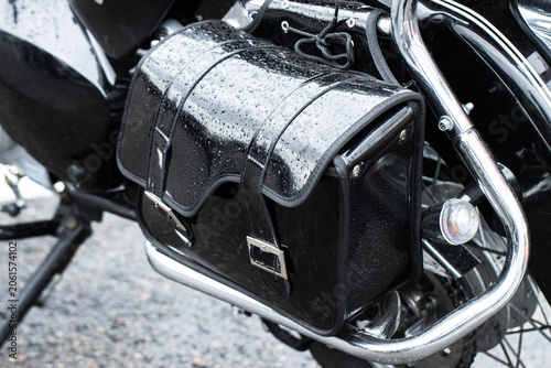 Foto Black leather motorcycle saddlebag covered in rain drops close up view chrome de