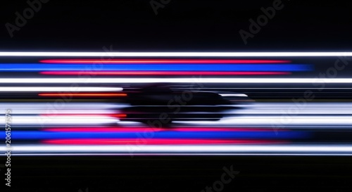 Sleek sports car speeding through a dark tunnel captured with extreme motion blur effect showing vibrant horizontal lines of red and blue glowing neon lights in a high speed photograph.