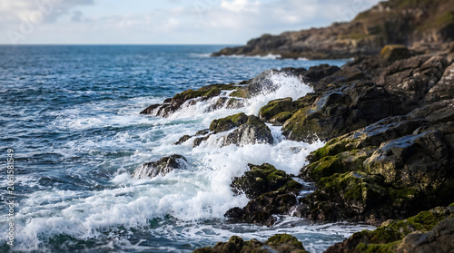 Waves crashing against rugged moss-covered rocks along the coastline