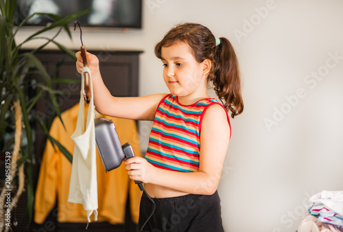 Tableau sur toile Girl ironing clothes with a handheld steamer at home