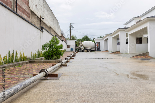 Long concrete pump pipeline connecting mixer truck to residential construction site during concrete slab pouring operation