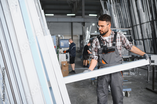 Fotografie Worker carrying pvc window profile in factory workshop