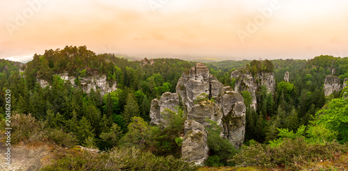 Rock city formations in Hruba Skala, Bohemian Paradise (Cesky raj), rising from forest seen from above. Orange sunrise sky lights sandstone towers and valleys panoramic view sky .