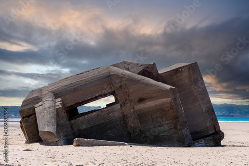 Ruin of old concrete bunker on tropical beach under stormy sky