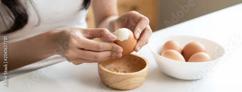 Bild auf Leinwand Close up of woman peeling boiled egg at white table, female hands cracking brown
