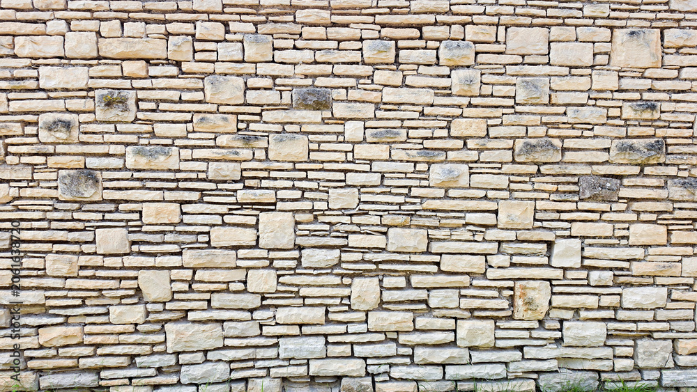 Obraz premium Textured Beige Stone Wall with Irregular Brick Pattern