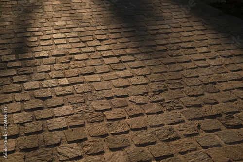 Cobblestones pavement texture pattern shadows lighting outdoor surface stone walkway in a moody rustic street scene captured with natural light and detailed texture.