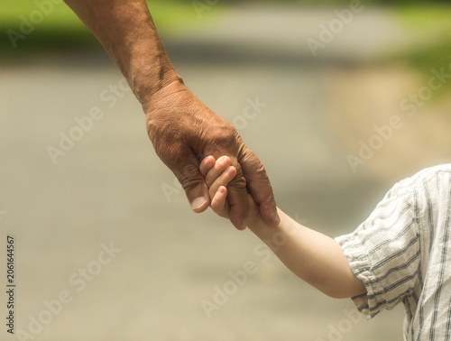 Happy senior man Grandfather with cute little boy grandson playing in field. The grandfather holds grandson in a lap park