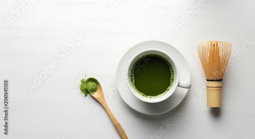 Matcha tea preparation powder cup and whisk on white wood surface