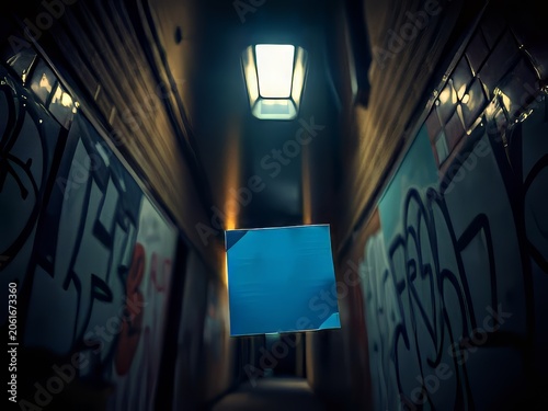 A blue square in a dark graffiti-lined alleyway with a single overhead light.