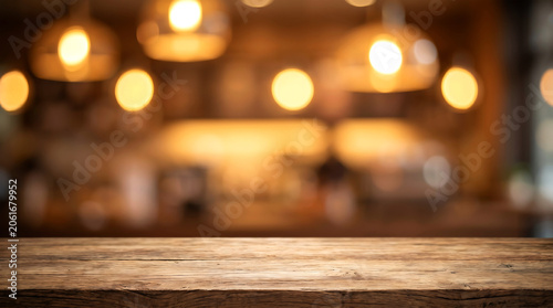 Rustic dark wood table with blurred cafe bar background and hanging warm lamps for beverage product display mockup