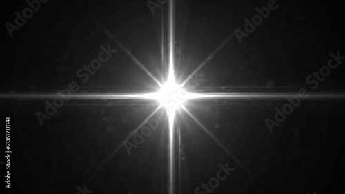 Bright white starburst light flash glowing on black background.