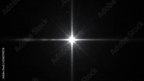 Bright white starburst light flash glowing on black background.