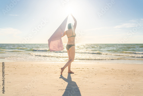 Woman standing with towel on the beach with ocean on background