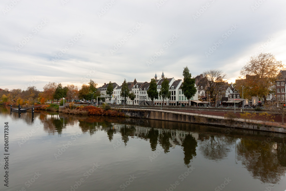 Fototapeta premium Scenic view of the Meuse river embankment with historic buildings reflected in water in Maastricht