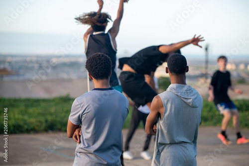 Basketball player taking a shot at the rim with defender jumping
