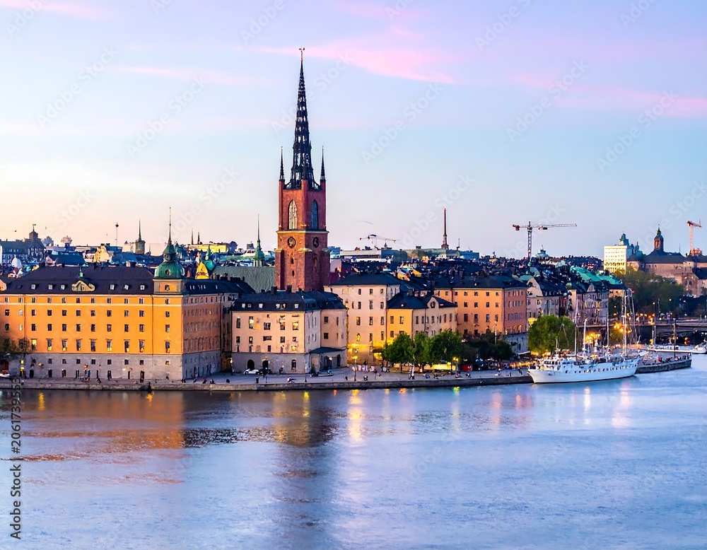 Fototapeta premium A serene cityscape at dusk, featuring a prominent church steeple, calm waters, and a blend of pastel hues in the sky