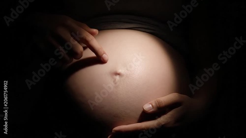 Pregnant woman cradling her bare belly with both hands