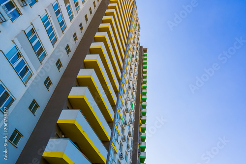 Bild auf Leinwand Low angle view of a modern multi story residential building with yellow balconie