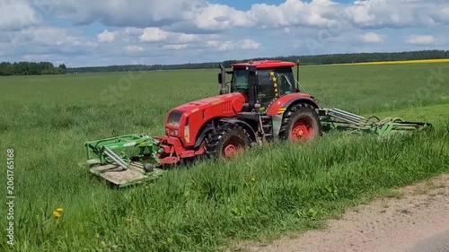 Mowing the grass in the field with a tractor. Summer harvesting of grass