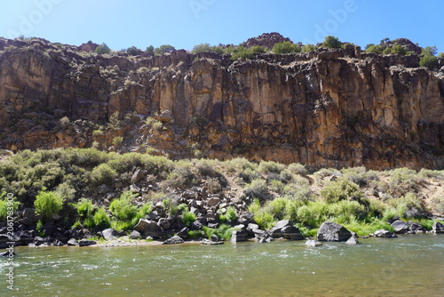Fotografie A horizontal, wide-angle shot capturing a rugged canyon landscape with a river flowing in the foreground