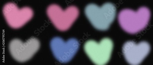Cute heart shapes in various pastel colors blurred on black background with trendy grainy noise filter.