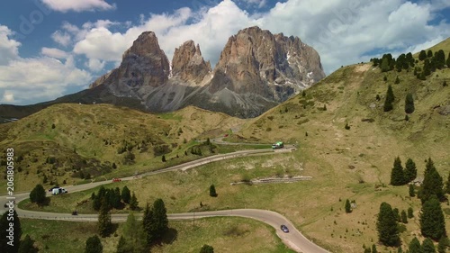 Alpine mountain landscape with winding road through green hills and peaks