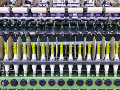 Symmetrical front view of automatic textile spinning machinery with white thread bobbins