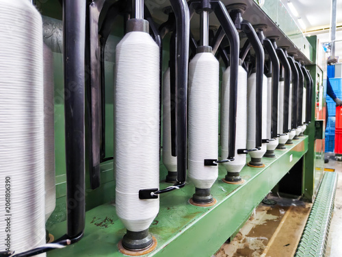 Automatic textile spinning machinery with white yarn spools in factory